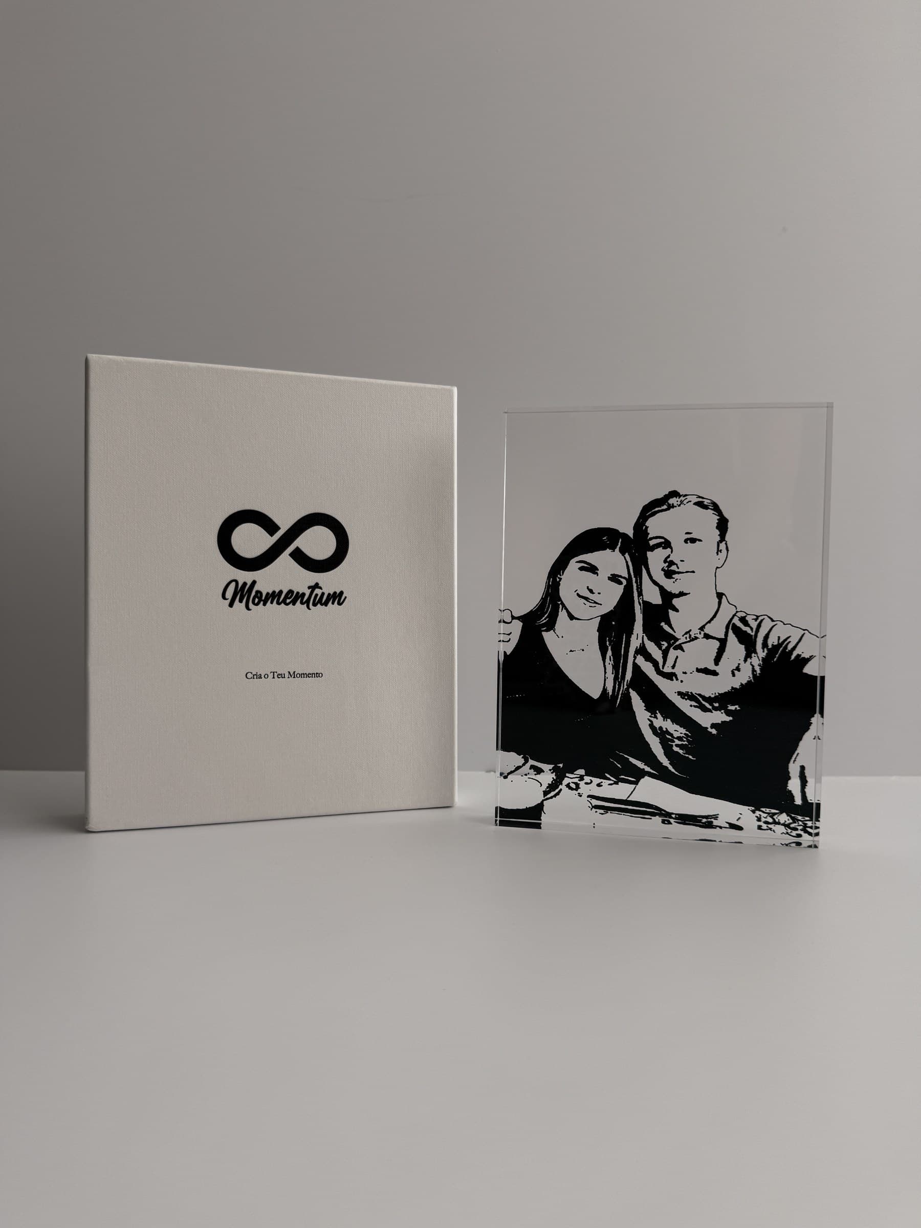 Bloco acrílico com um casal em gravura artística, ao lado da caixa Momentum